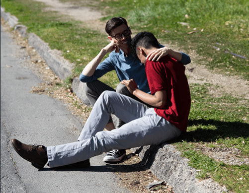 Two people sitting on the grass and laughing